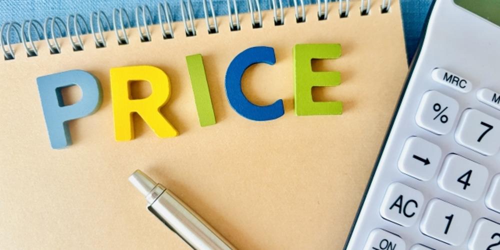 PRICEの文字とノート、ペン、電卓が写った価格計算をイメージさせる写真