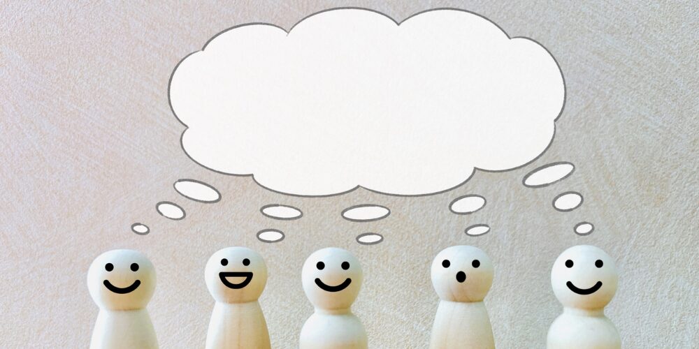 木製ピン人形と大きな吹き出しで表す口コミイメージ