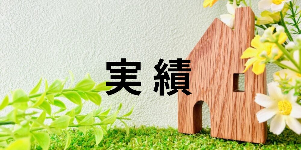 木製の家のオブジェと白や黄色の花、緑の芝の上に「実績」の文字が配置されたイメージ、成果や信頼を表現