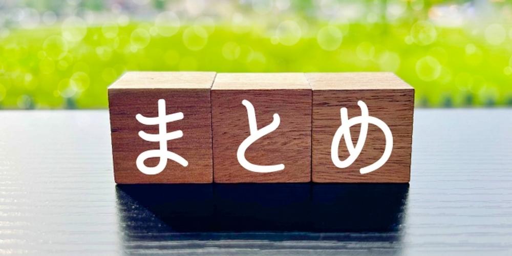 木製ブロックに「まとめ」と書かれた文字と、背景に広がる緑豊かな風景。