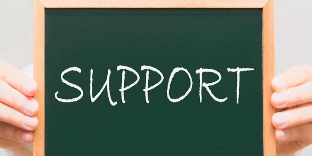 「SUPPORT」と書かれた黒板を両手で持つ人物のイメージ、支援やサポートのコンセプトを表現