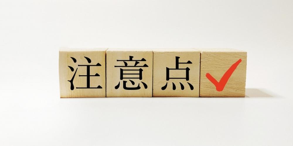 注意点の文字と赤いチェックマークが描かれた木製ブロックの画像