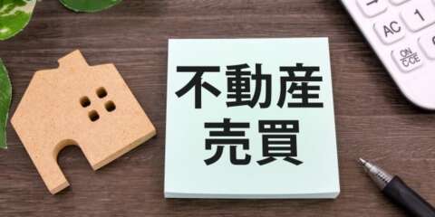 不動産売買の手続きや契約をイメージした木製の家とメモ帳の写真
